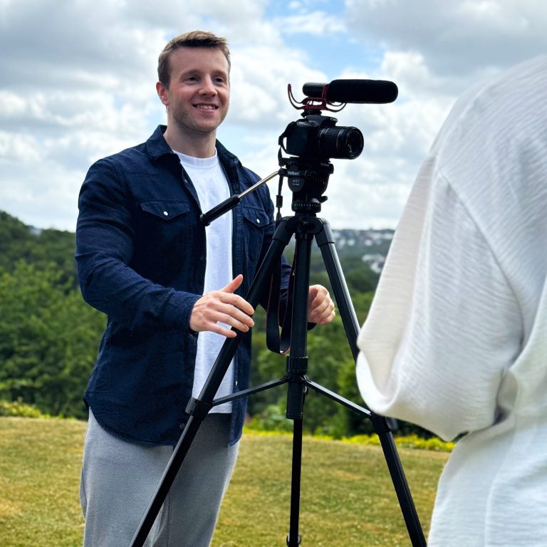 Videograf Sebastian Pixberg lachend hinter der Kamera in einem Gespräch mit einem Kunden
